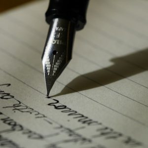 Fountain pen amending handwritten text on paper